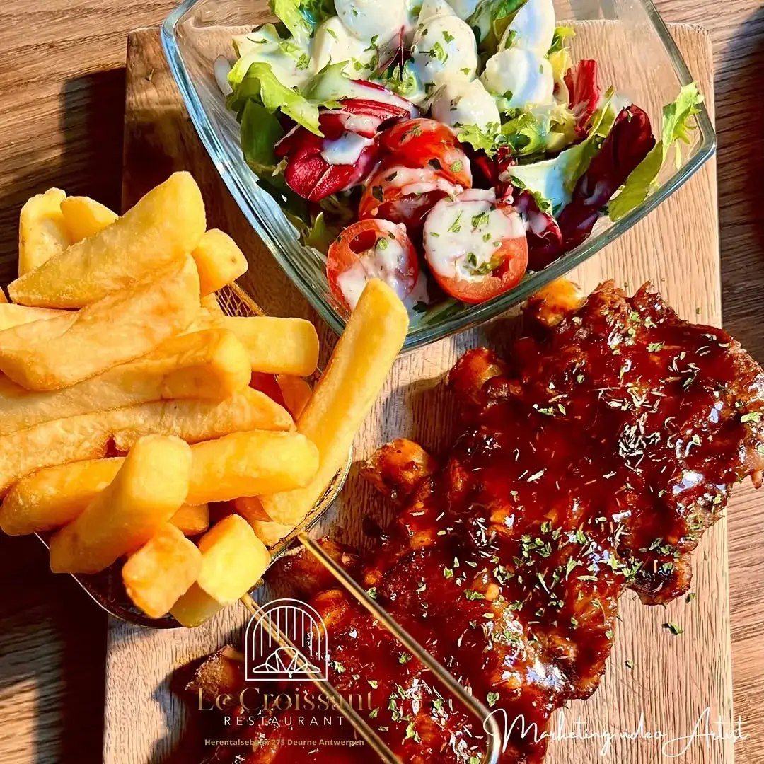 Spare ribs met barbecuesaus, verse frieten en een frisse salade op een houten plank